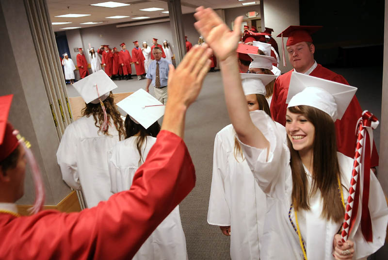 Cony High School class of 2012 marshall Natalie Arbour exchanges a high-five with classmate Dylan Cheever during their graduation ceremony Sunday in Augusta.