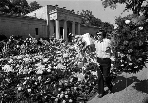 In this Aug. 18, 1977 file photo, a florist adds more floral arrangements to the overflowing collection of flowers that cover the ground at the mausoleum where singer Elvis Presley will be entombed during funeral services today in Memphis, Tenn. Celebrity auctioneer Darren Julien says the crypt inside the granite and marble mausoleum where Presley was originally entombed at the Forest Hill Cemetery in Memphis, Tenn., will be part of his "Music Icons" auction on June 23 and 24, 2012, in Beverly Hills, Calif. (AP Photo, File)