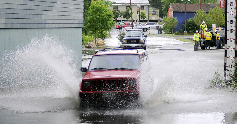 Matt LeClair drives through the flooding Cobbossee Stream in Gardiner on Monday afternoon while evacuating a friend's vehicle. The arcade lot, along Cobbossee Stream, flooded following heavy rain.