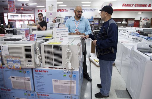 Salesman Carlos Burgos, center, helps customer Raven Campbell select an air conditioner at P.C. Richard & Son, an electronics and appliance store on Tuesday in the Brooklyn borough of New York.