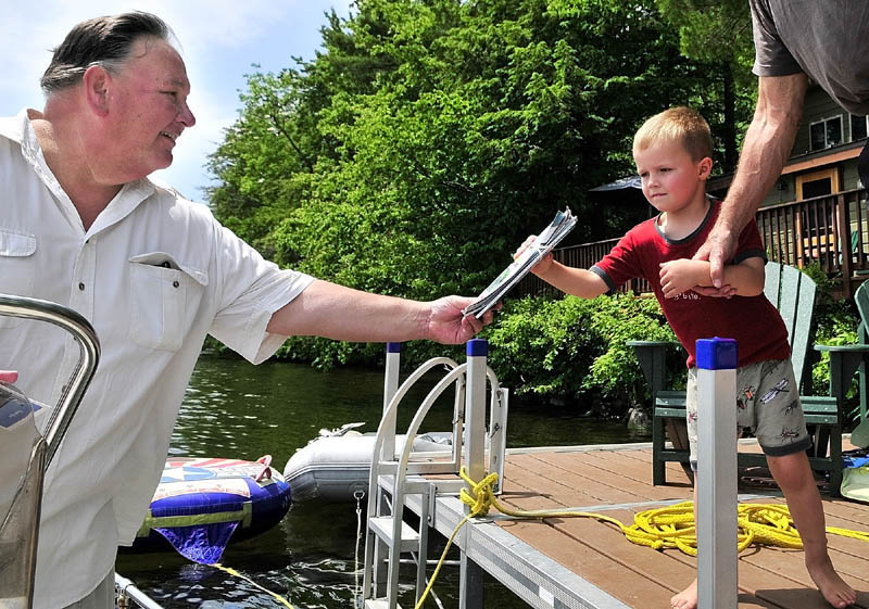 Norm Shaw, left, hands off the mail to a youngster while making deliveries from his boat on Thursday in Belgrade.