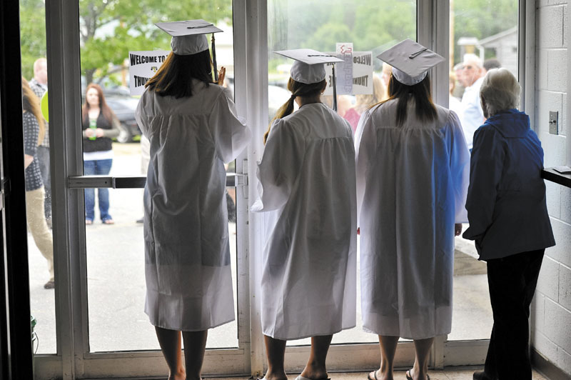 ON THE LOOKOUT: Left to right, Daisy Obert of Anson, Brook Gardiner of New Portland and Tiffany Mayo of North Anson, and an unidentified onlooker, peek out the school’s front doors looking for family before the ceremony starts.