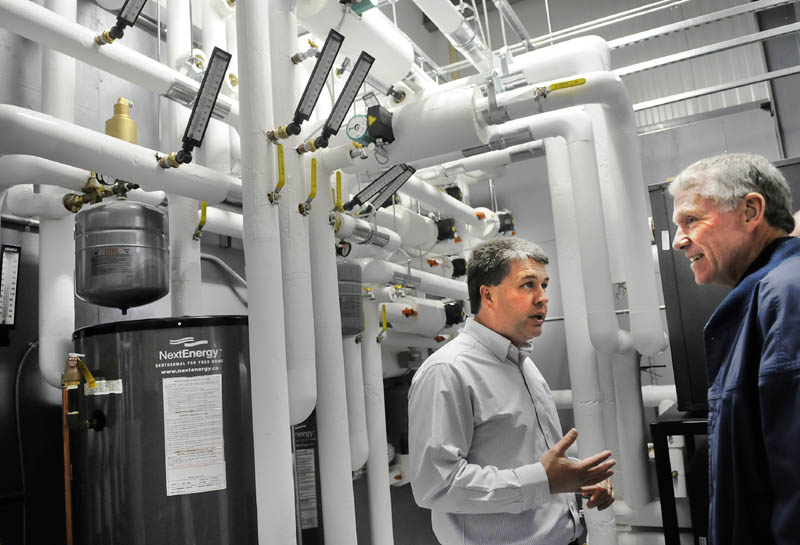 O’Connor Chevy, Buick, GMC and Cadillac owner Randy Hutchins, left, explains the geothermal heating system he installed in the new 18,000-square-foot Augusta dealership to Gary Hammond during the grand opening on Monday. The auto business is heated and cooled by a climate control system, which uses 18 wells, up to 360 feet deep, drilled into the earth beneath the parking lot and building. Hamm