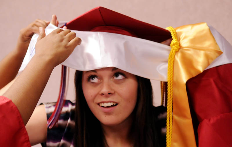 Oak Hill High School senior Jane Marston gets some help getting dressed from classmates Monday evening before commencement exercises at the Augusta Civic Center. A total of 89 students from Sabattus, Litchfield and Wales graduated.