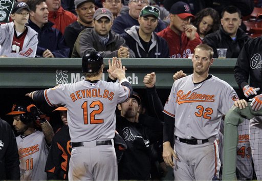 Baltimore Orioles' Mark Reynolds (12) is greeted at the dugout by Matt Wieters (32) and other teammates after he scored on a single by Ronny Paulino during the 10th inning of a baseball game at Fenway Park in Boston on Tuesday, June 5, 2012. The Orioles won 8-6. (AP Photo/Elise Amendola)