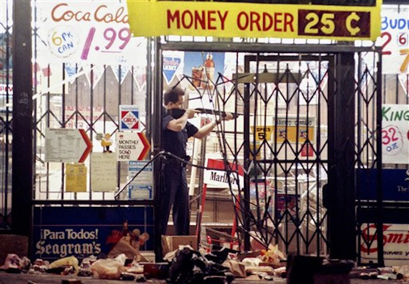 In this April 30, 1992 file photo, a Los Angeles police officer takes aim at a looter in a market at Alvarado and Beverly Boulevard in Los Angeles during the second night of rioting in the city. Rodney King, the black motorist whose 1991 videotaped beating by Los Angeles police officers was the touchstone for one of the most destructive race riots in the nation's history, has died, his publicist said Sunday, June 17, 2012. He was 47. (AP Photo/John Gaps III, File)