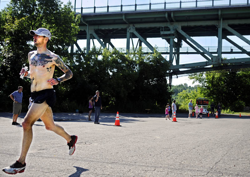 FIRST TO THE LINE: Seth Hasty runs beneath Memorial Bridge in Augusta to finish first in the Kennebec River Rail Trail Half Marathon on Sunday.