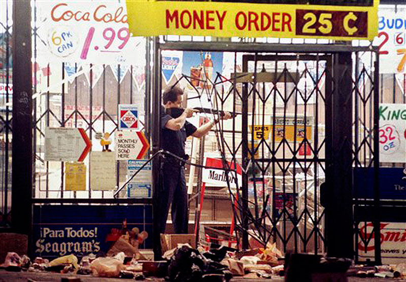 In this April 30, 1992 file photo, a Los Angeles police officer takes aim at a looter in a market at Alvarado and Beverly Boulevard in Los Angeles during the second night of rioting in the city. Rodney King, the black motorist whose 1991 videotaped beating by Los Angeles police officers was the touchstone for one of the most destructive race riots in the nation's history, has died, his publicist said Sunday, June 17, 2012. He was 47.(AP Photo/John Gaps III, File)