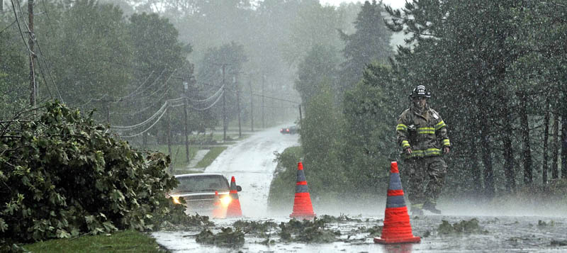 Staff Photo by Michael G. Seamans A Fairfield firefighter sets up cones to redirect motorists around downed power lines and tree limbs from a powerfull storm that rolled through central Maine Friday afternoon.
