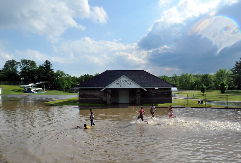 Staff Photo by Michael G. Seamans Children runs through the flooded parking lot at the Alfond Municipal Pool on North Street as a powerful storm rolled through Waterville Friday afternoon.