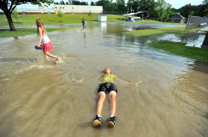 Staff Photo by Michael G. Seamans Zack Taylor, 13, floats on his back in the flooded parking lot at the Alfond Municipal Pool on North Street in Waterville Friday.