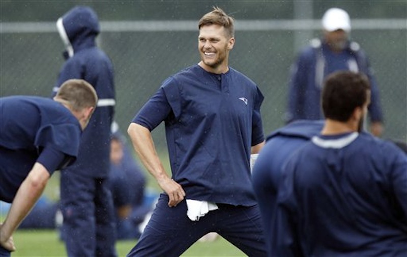 New England Patriots quarterback Tom Brady smiles while stretching during NFL football practice in Foxborough, Mass., Wednesday, June 13, 2012. (AP Photo/Charles Krupa)