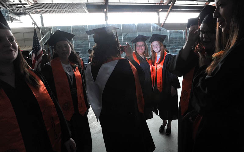 Staff Photo by Michael G. Seamans Brittni Martell,left center, and Maddie Daily, right, center are illuminated by a camera flash asWinslow High School's class of 2012 prepare for commencement ceremonies in Alfond Rink prio to the ceremonies in Wadsworth Gymnasium at Colby College in Waterville on Wednesday.
