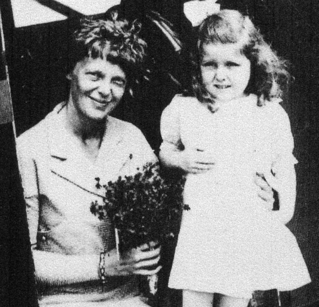 Amelia Earhart receives flowers from 5-year old Gladys Chase, of Augusta, on Aug. 14, 1934, at the Augusta airport. The two were photographed in the doorway of a Boston & Maine Airways Stinson SM-6000B passenger plane.