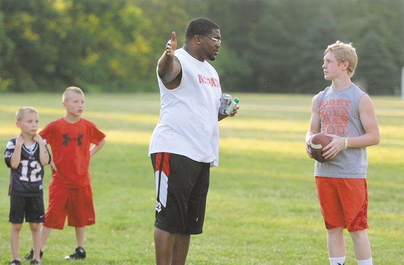 COACHING THE KIDS: Former New England Patriots fullback Patrick Pass gives some advice to Austin Pelletier, 12, of Sidney on Friday while helping coach the annual Central Maine Youth Football Clinic in Waterville.