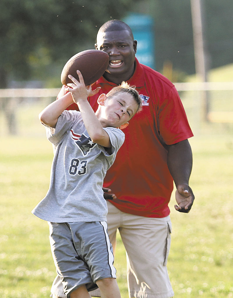 A DAY AT THE CLINIC: Former New England Patriots fullback Harold Shaw watches as Elijah Roberge, 9, of Sidney try to catch a pass Friday during the annual Central Maine Youth Football Clinic in Waterville.