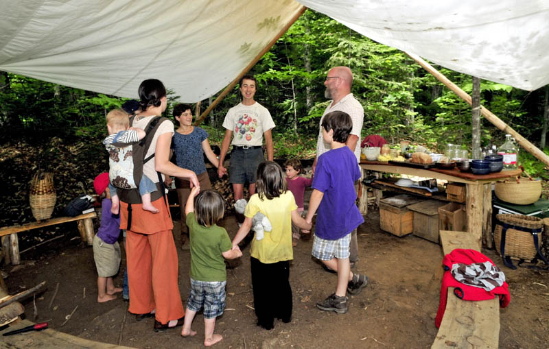 COMMUNAL LUNCH: The host Knapp family and visiting Soule family came together prior to a lunch under a tent at the Koviashuvik School in the woods in Temple on Thursday. Chris Knapp, center, leads the gathering.