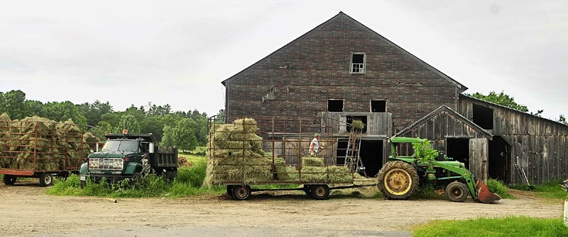 Berndt Graf loads bales onto a hay elevator on Tuesday afternoon at the 256-acre Meadow Brook Farm on Bamford Hill Road in Fayette. The Kennebec Land Trust just completed a deal with the Grafs which allows a conservation easement and opens some areas to the public.