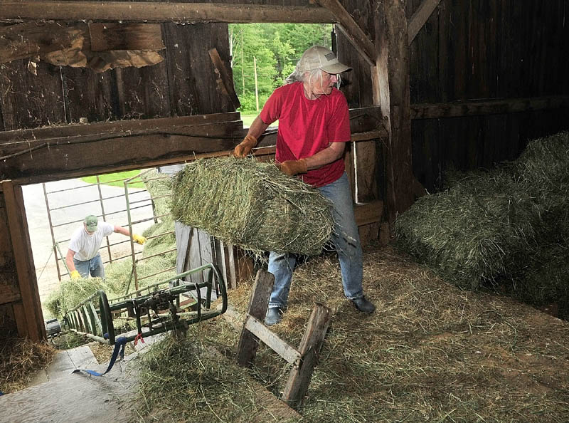 Berndt, left, and Elaine Graf load hay bales into a barn on Tuesday afternoon at the 256-acre Meadow Brook Farm on Bamford Hill Road in Fayette. The Kennebec Land Trust just completed a deal with the Grafs which allows a conservation easement and opens some areas to the public.
