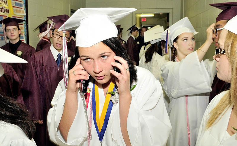 MULTI-TASKING: Maine Central Institute graduate Allison Sinclair has her hands full with a cellphone in each ear moments before the seniors took part in commencement exercises in Pittsfield on Sunday.