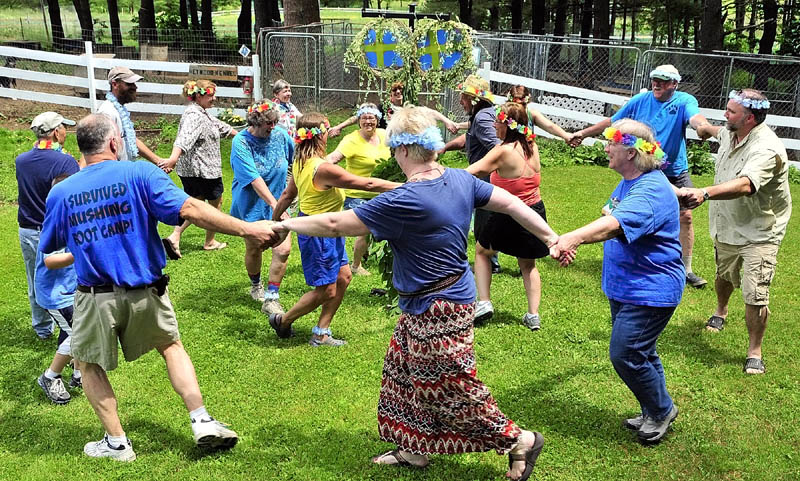 Two rings of people dance in opposite directions around a midsommarstang, or Swedish mid-summer pole, during the the Midsommar Celebration on Saturday at Heywood Kennels in Augusta.