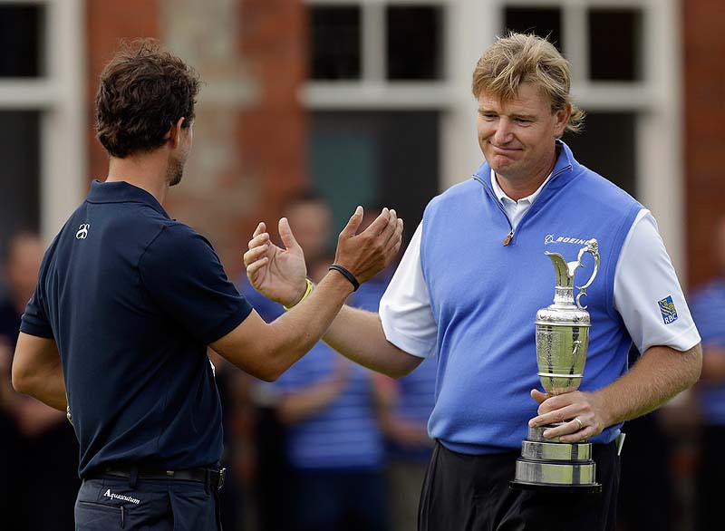 Ernie Els holds the Claret Jug trophy after winning the British Open today, and shakes hands with Adam Scott, who had the lead until bogeying the final four holes at Royal Lytham & St Annes golf club, Lytham St Annes, England.