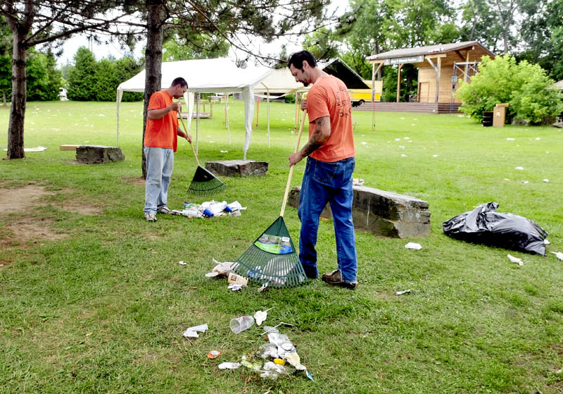 PARTY'S OVER: On Thursday Kennebec County Jail inmates Michael Meader, left, and Ryan Willey rake litter left over from the Winslow Family 4th of July events at Fort Halifax Park in Winslow. The men are participating in a jail community service program.