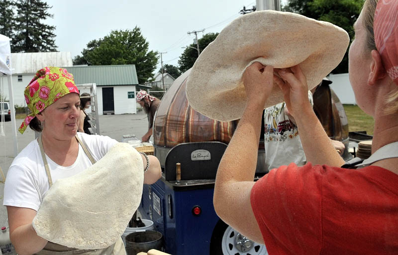 Amber Lambke, left, director of the Maine Grain Alliance, and Katherine Creswell, right, hand toss pizza dough at the Maine Grain Alliance pizza tent at the Artisan Bread Fair at the Skowhegan State Fairgrounds Saturday.