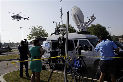 Reporters watch as a police helicopter lands today at a staging area for an investigation into the fatal yacht capsize in Oyster Bay, N.Y.