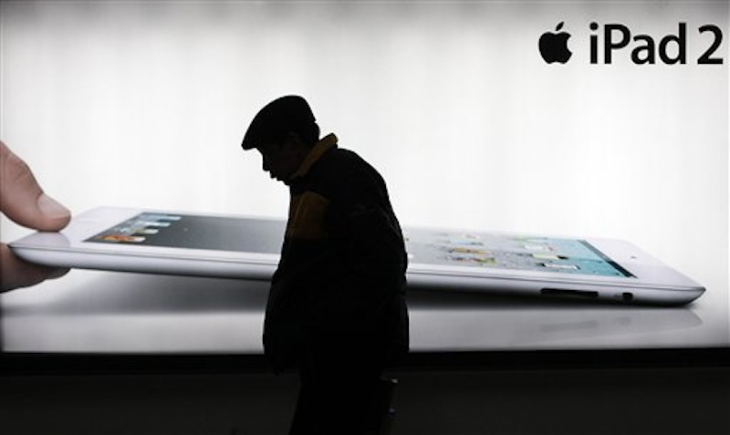 In this Feb. 28, 2012 file photo, a man walks by an advertisement of Apple's iPad 2 in Shanghai, China. Apple has agreed to pay China's Shenzhen Proview Technology $60 million to settle a dispute over ownership of the iPad name, a court announced Monday, July 2, 2012, removing a potential obstacle to sales of the popular tablet computer in the key Chinese market. (AP Photo/Eugene Hoshiko, File)
