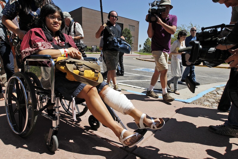 Rita Paulina, in wheelchair, who was injured in the attack, departs the Arapahoe County Courthouse after an arraignment hearing for accused theater shooter James Holmes, Monday, July 30, 2012 in Centennial, Colo. Colorado prosecutors filed formal charges Monday against Holmes, the former neuroscience student accused of killing 12 people and wounding 58 others at an Aurora movie theater. (AP Photo/Alex Brandon)