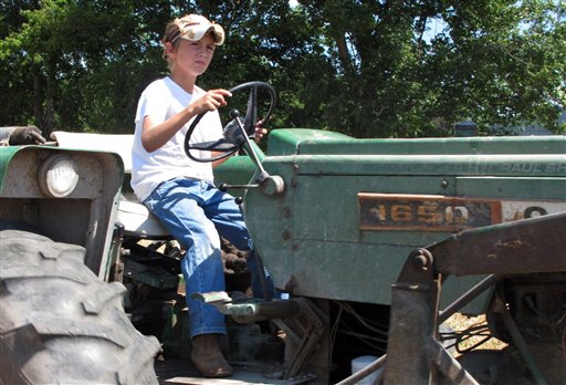 Jacob Mosbacher, 10, drives a tractor through a bean field on his grandparents' property near Fults, Ill., recently. Agriculture organizations and federal lawmakers from farm states succeeded last spring in convincing the U.S. Labor Department to drop proposals limiting farm work by children such as Jacob, whose parents say such questions of safety involving kids should be left to parents.