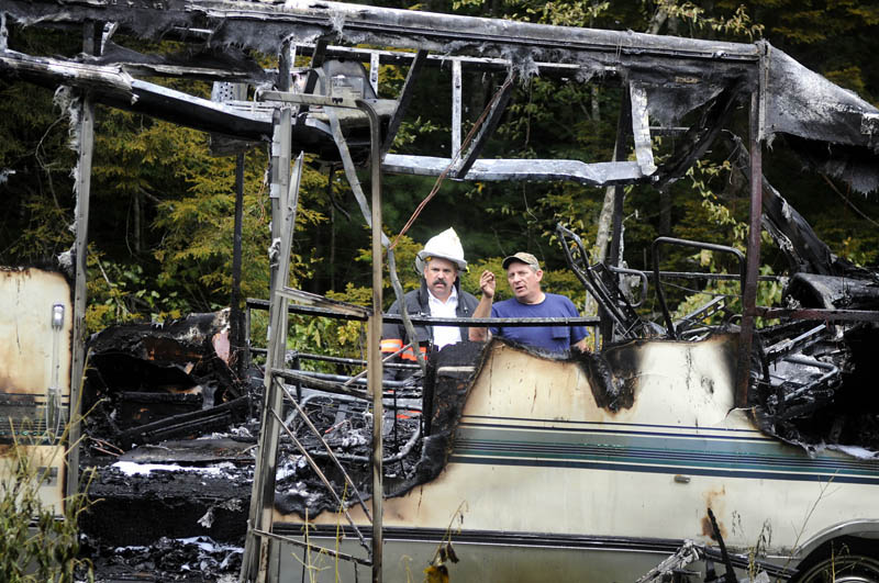 IMMOBILE: Richard Hutchings, right, assesses the smoldering frame of his recreational vehicle Thursday with Gardiner Fire Chief Mike Minkowsky after a blaze outside Hutchings' Gardiner home destroyed the vehicle. No injuries were reported, according to firefighters.