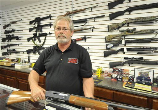 Randy Hodges displays a firearm at the Gun Vault in High Point, N.C., on Monday. Gun sales have jumped after the mass shooting last week in Colorado. (AP Photo / Sonny Hedgecock)
