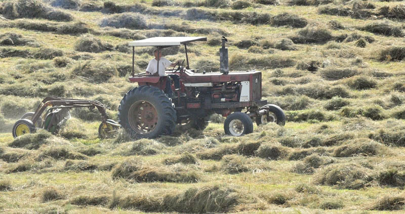 Staff photo by Joe Phelan A tractor operator turns cut grass for hay on Thursday afternoon in Hallowell. The weather forecast calls for a mostly sunny weather through the weekend.