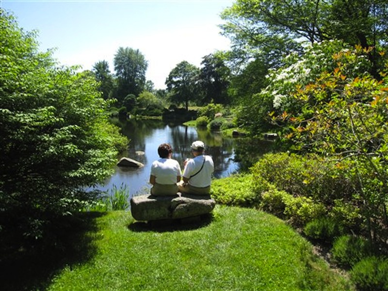In this July 12, 2012 photo, visitors sit on a rock bench to view the scenery at the Asticou Azalea Garden pond in Northeast Harbor, Maine. The garden includes plants from the collection of renowned landscape designer Beatrix Farrand, who has connections to several gardens in the area, including the nearby Abby Aldrich Rockefeller Garden, a private garden thatís only open to the public a few days a year. (AP Photo/Beth J. Harpaz)