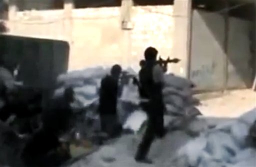 This image made from amateur video released by the Ugarit News and accessed Sunday, July 15, 2012, purports to show Free Syrian Army soldiers clashing with Syrian government forces in Damascus, Syria. Syrian troops and rebels clashed inside Damascus for a second day on Monday, causing plumes of black smoke to drift over the city's skyline in some of the worst violence in the tightly controlled capital since the country's crisis began 16 months ago.