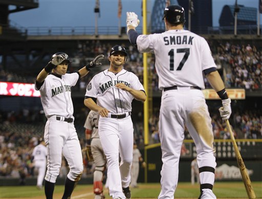 Seattle Mariners' Casper Wells, center, and Ichiro Suzuki, left, are greeted by Mariners' Justin Smoak as they score in the sixth inning of a baseball game, Saturday, June 30, 2012, in Seattle. (AP Photo/Ted S. Warren)