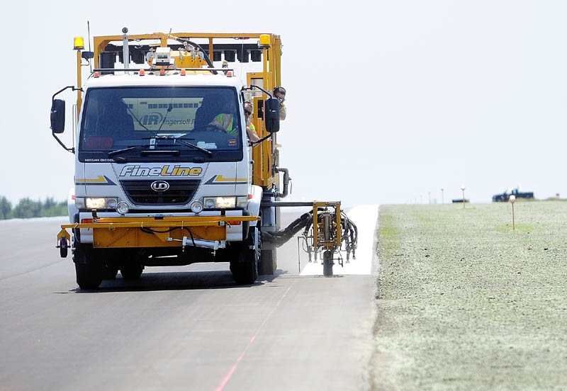 A truck paints a stripe on the edge of the newly repaved runway that reopened at the Augusta State Airport. Part of the project included narrowing the width of the runway, which the newly reseeded lawn on the right side shows.