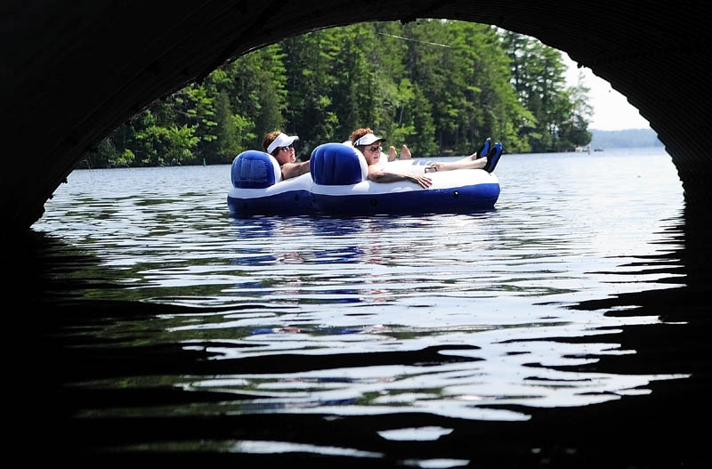 Carol Hummel, left, and Fran Mollis, both of New Jersey, drift past a culvert as they relax on a raft on a hot sunny Friday afternoon on Long Pond in Belgrade. The women said that this was the 36th summer that they'd been coming to Castle Island Camps and now they bring their children and grandchildren up for a week every summer.
