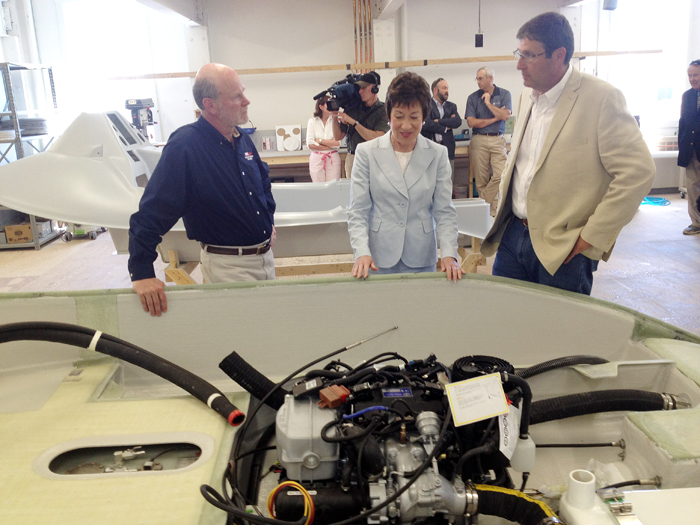 Flanked by David Packhem, president and CEO of Hodgdon Defense, left, and Tim Hodgdon, owner of Hodgdon Yachts, Sen. Susan Collins inspects the hull of the Greenough Advanced Rescue Craft during a tour of the facility in Bath today.