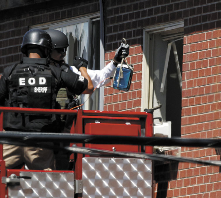 Members of law enforcement wearing body armor and helmets prepare to what ATF sources describe as a"water shot" in the apartment of alleged gunman James Holmes on Saturday in Aurora, Colo. The "water shot" is exploded and used to disrupt the device.