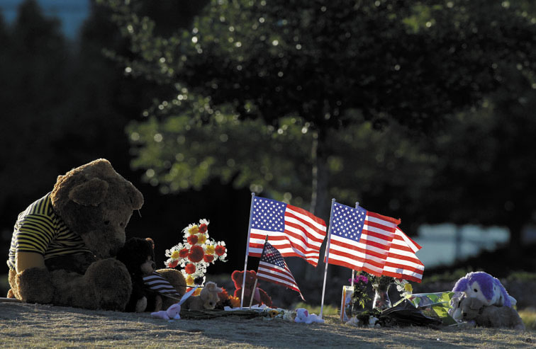 The sun rises between flags placed at a memorial near the Century 16 movie theater on Sunday in Aurora, Colo. Twelve people were killed and dozens were injured in a shooting attack early Friday at the packed theater during a showing of "The Dark Knight Rises."