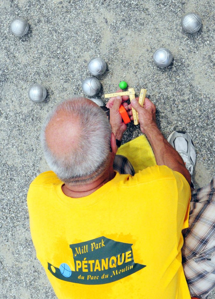 Referee Michel Voyer, from Wissous, France, measures the distance between the green target ball, called a cochonnet, and the larger boules tossed by players to see which got closer during the Festival de la Bastille on Saturday afternoon in Augusta.