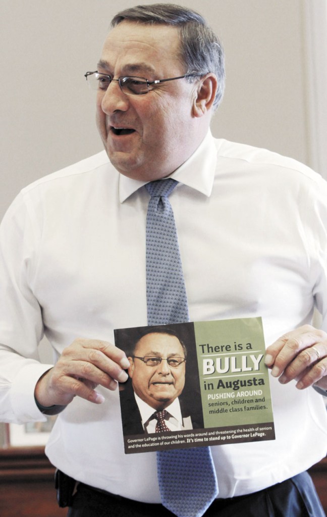 In this Friday, April 27, 2012 photo, Gov. Paul LePage talks about his sense of humor while holding a poster that reads "There is a bully in Augusta pushing around seniors, children and middle class families," during an interview with the Associated Press at his office at the State House in Augusta. Critics are putting pressure on LePage to apologize for referring to the Internal Revenue Service as "the new Gestapo" during his radio address Saturday.