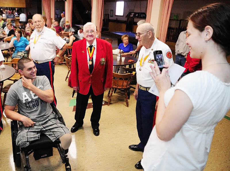 Jeremy Gilley, left, smiles as Rachel Turcotte snaps a photo of him with members of the Marine Corps League Detachment # 599 at a fundraiser held on Wednesday night at Le Club Calumet in Augusta. The older Marines made service rivalry jokes with Army veteran Gilley.