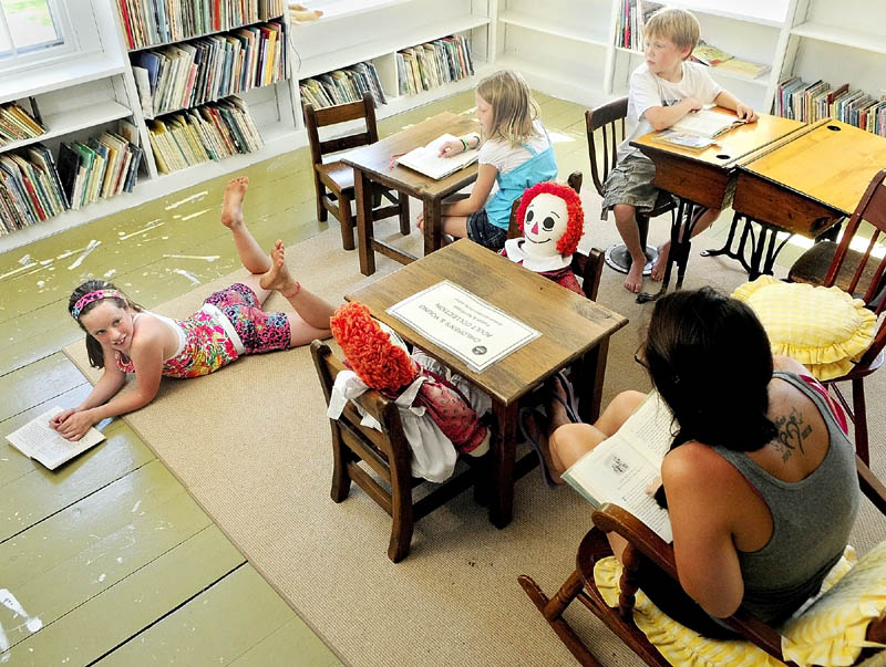 Norah Davidson, left, Reece McGlew, Wes McGlew and their nanny, Amelia Jackson, far right, read books in the children's room on Thursday afternoon at the Albert Church Brown Memorial Library in China Village.