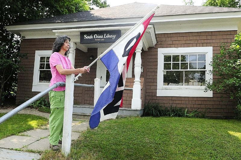 Volunteer Linda Gray puts out the open flag on Saturday morning at the South China Public Library.