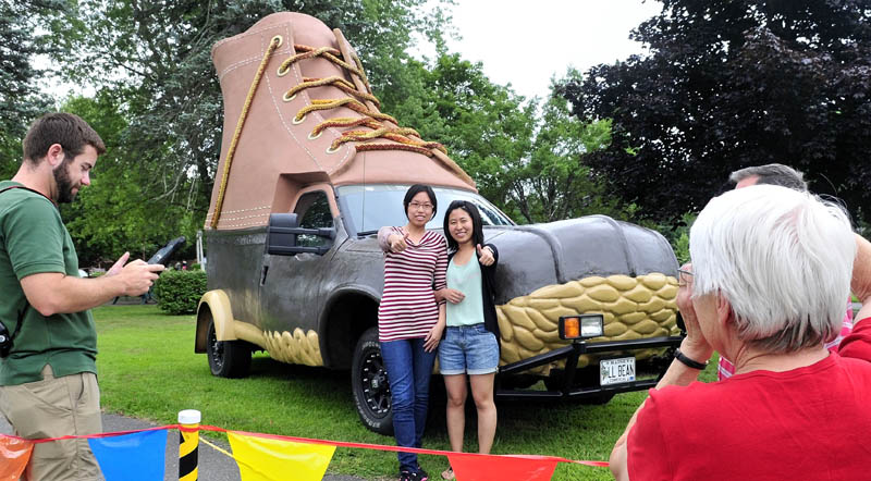 Regina Oliver photographs visiting students Amanda Xiao, left, and Mona Wang in front of the L.L. Bean Bootmobile at Gifford's Ice Cream in Waterville on Sunday as part of the Freeport company's 100th anniversary. Oliver and husband Herb are hosting the students and said, "We wanted to show them an iconic Maine company like L.L. Bean today." Eric Smith, left, drove the vehicle.