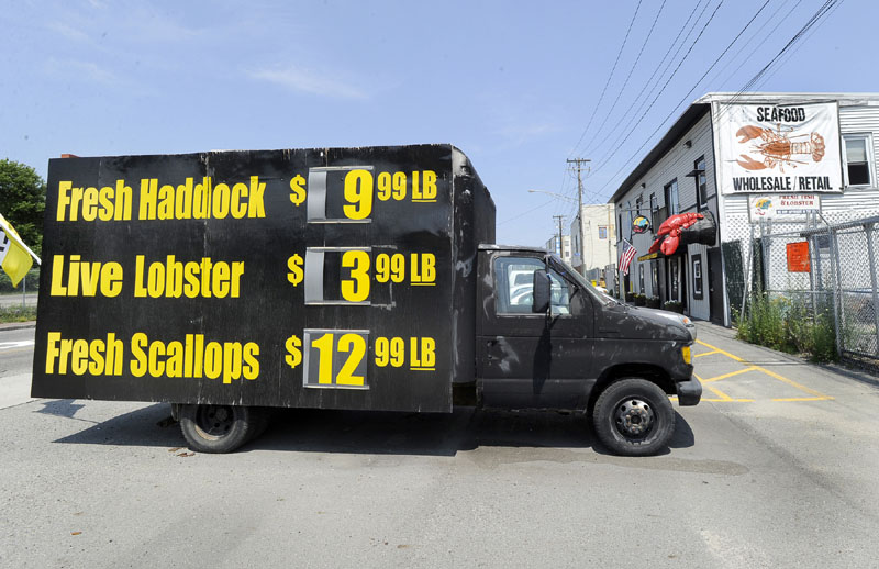 Signs on the side of a truck Friday show how cheap lobsters are at Free Range Fish & Lobster market in Portland.